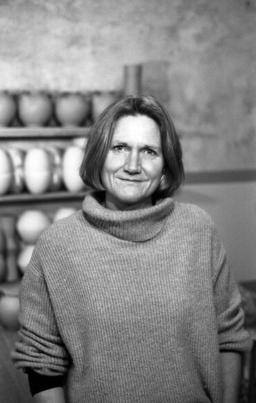 Eine Frau mit schulterlangen Haaren vor einem regal mit Töpferwaren